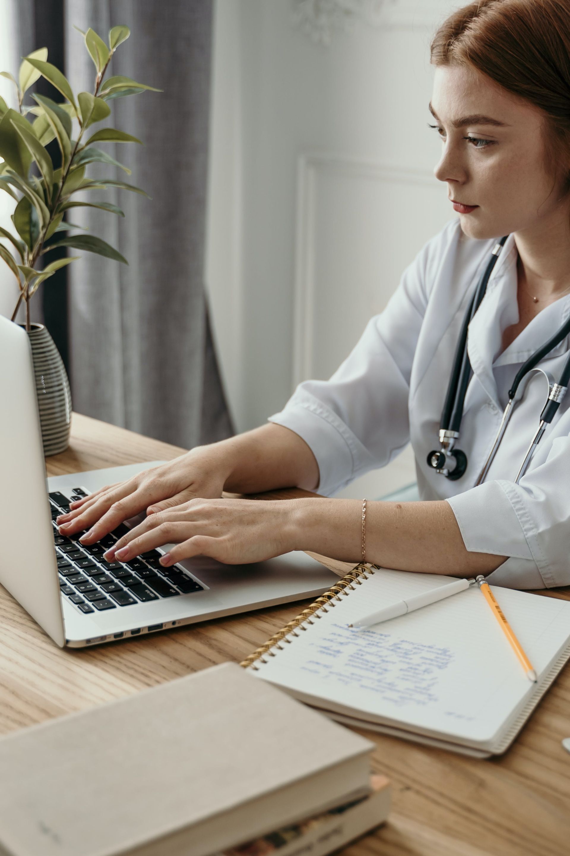 A Woman in White Long Sleeves Typing on Her Laptop